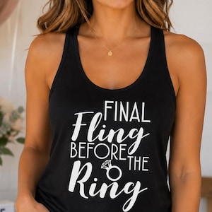 May include: Black tank top with the text "FINAL FLING BEFORE THE RING" in white script. The tank top is a racerback style. The model is wearing denim shorts and a gold necklace. The image has a bridal theme.
