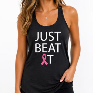 May include: Black racerback tank top with the text "JUST BEAT &T" in white, and a pink ribbon graphic. The tank top is a dark color and has a scoop neck.