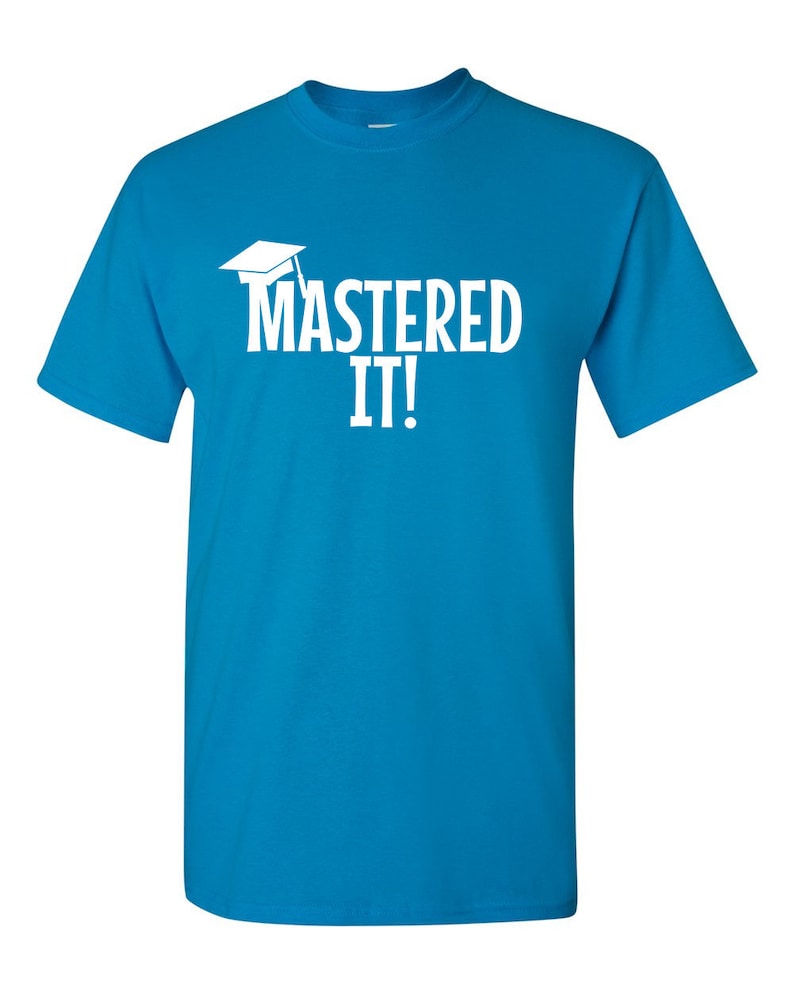 K&ouml;nnte beinhalten: T&uuml;rkisblaues T-Shirt mit dem wei&szlig;en Schriftzug "MASTERED IT!" und einer wei&szlig;en Abschlusskappe. Das T-Shirt hat einen Rundhalsausschnitt und kurze &Auml;rmel.