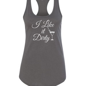 May include: A dark gray racerback tank top with the phrase "I Like it Dirty" in white script, accompanied by a martini glass graphic. The tank top has a scoop neck and a curved hemline.