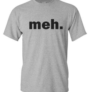 May include: A heather gray t-shirt with the word "meh." printed in black block letters. The shirt has short sleeves and a crew neck. The text is centered on the chest.