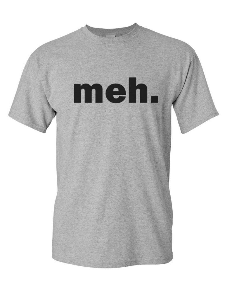 May include: A heather gray t-shirt with the word "meh." printed in black block letters. The shirt has short sleeves and a crew neck. The text is centered on the chest.