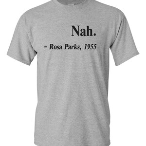 May include: A heather gray t-shirt with the word "Nah." printed in black, followed by "- Rosa Parks, 1955." The short-sleeved shirt is made of a soft material and is suitable for casual wear.