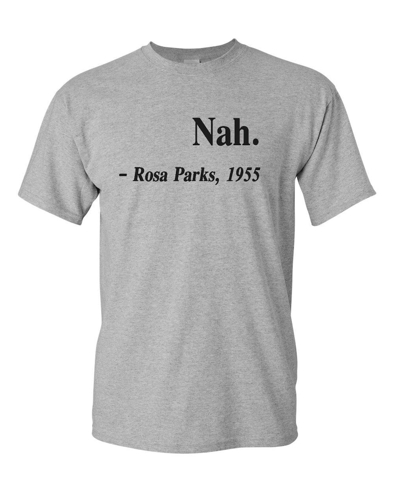 May include: A heather gray t-shirt with the word "Nah." printed in black, followed by "- Rosa Parks, 1955." The short-sleeved shirt is made of a soft material and is suitable for casual wear.
