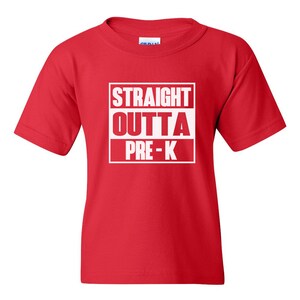 May include: A red t-shirt with the words "STRAIGHT OUTTA PRE-K" printed in white within a white rectangular box. The shirt is a short-sleeved crew neck style, suitable for children.