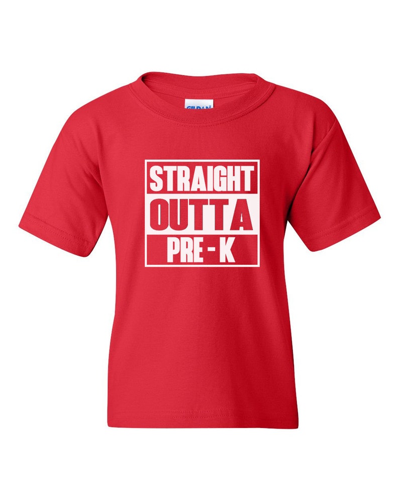 May include: A red t-shirt with the words "STRAIGHT OUTTA PRE-K" printed in white within a white rectangular box. The shirt is a short-sleeved crew neck style, suitable for children.