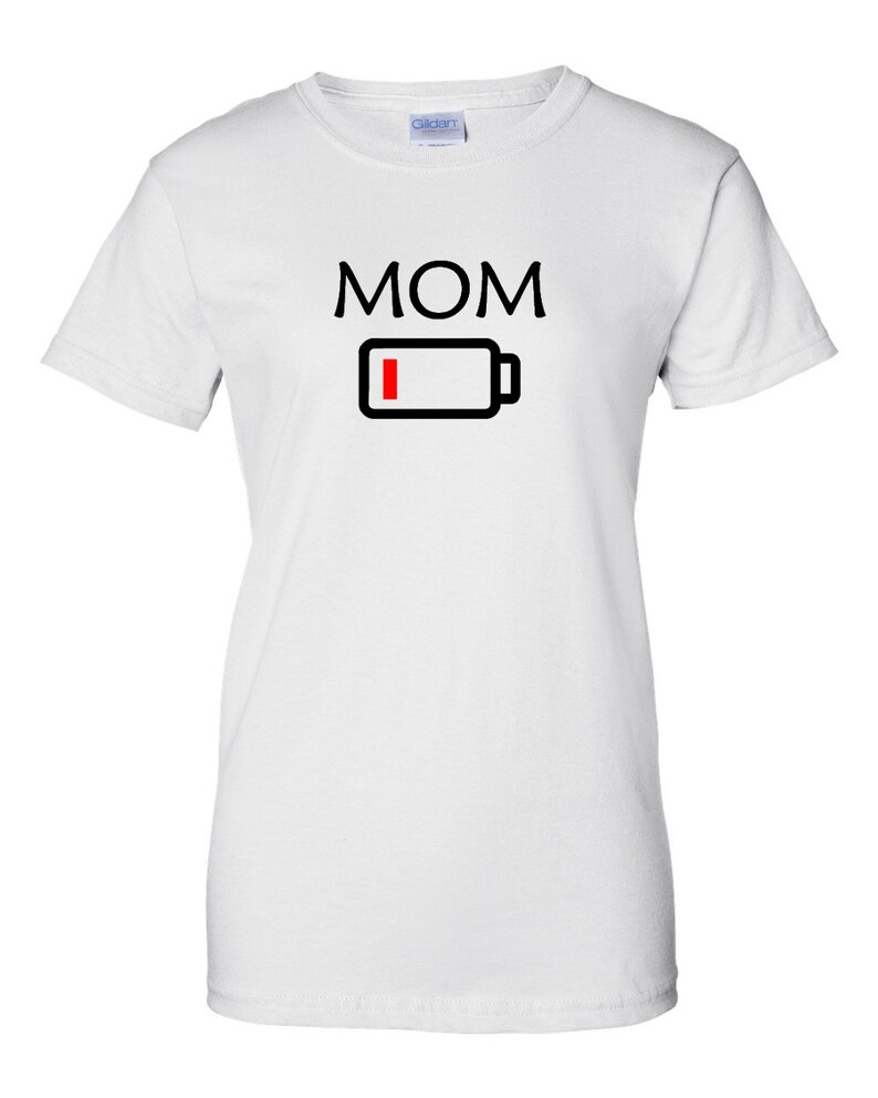 Pu&ograve; includere: T-shirt bianca con la scritta "MOM" in lettere maiuscole nere sopra un'icona di batteria nera con una barra rossa che indica batteria scarica. La maglietta &egrave; a girocollo.