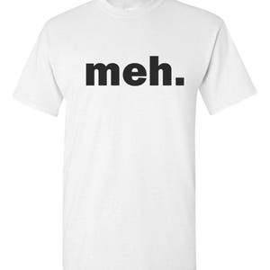 May include: White t-shirt with the word "meh." printed in bold, black letters. The shirt has short sleeves and a crew neck. The text is centered on the front of the shirt.