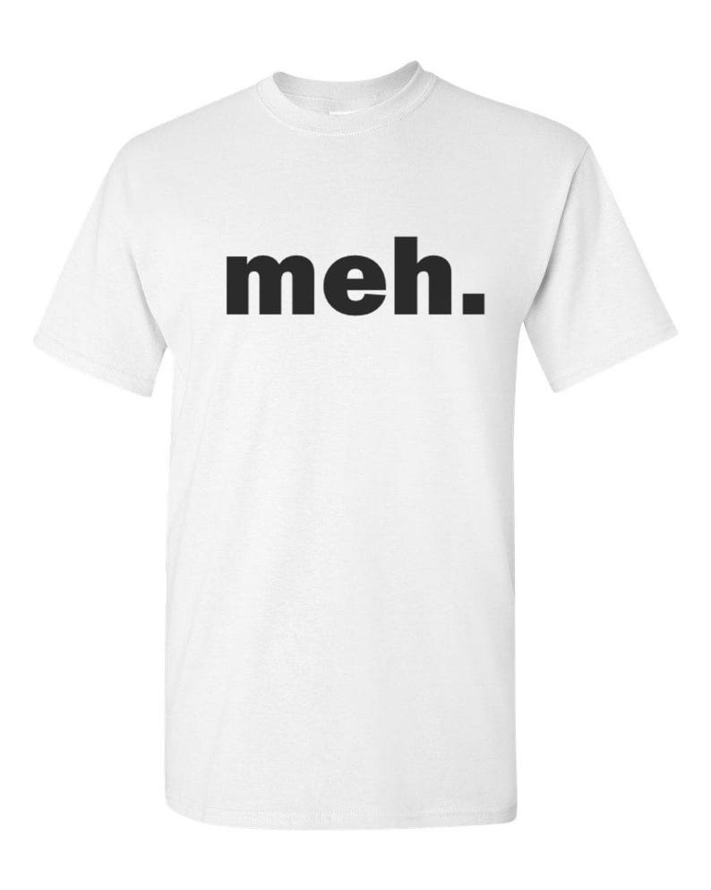 May include: White t-shirt with the word "meh." printed in bold, black letters. The shirt has short sleeves and a crew neck. The text is centered on the front of the shirt.