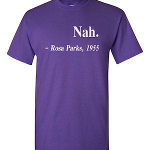 May include: A purple t-shirt with the text "Nah." above "- Rosa Parks, 1955" in white lettering. The shirt has short sleeves and a crew neck.
