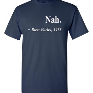 May include: Navy blue t-shirt with the word "Nah." in white, followed by "- Rosa Parks, 1955." The shirt is a classic crew neck style.