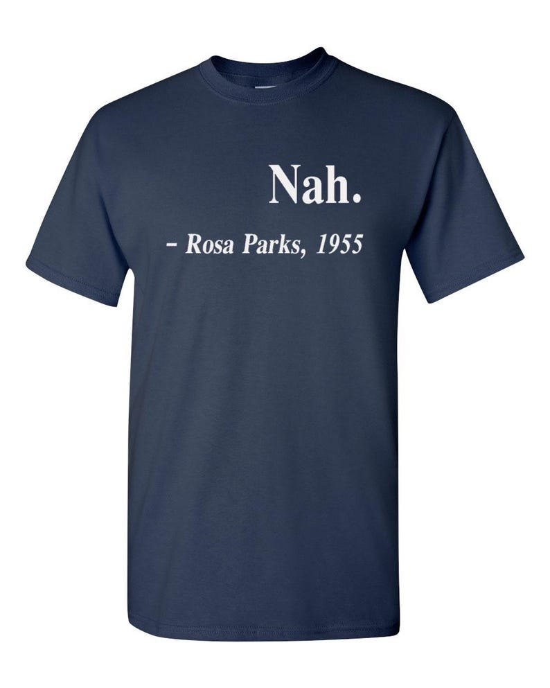 May include: Navy blue t-shirt with the word "Nah." in white, followed by "- Rosa Parks, 1955." The shirt is a classic crew neck style.