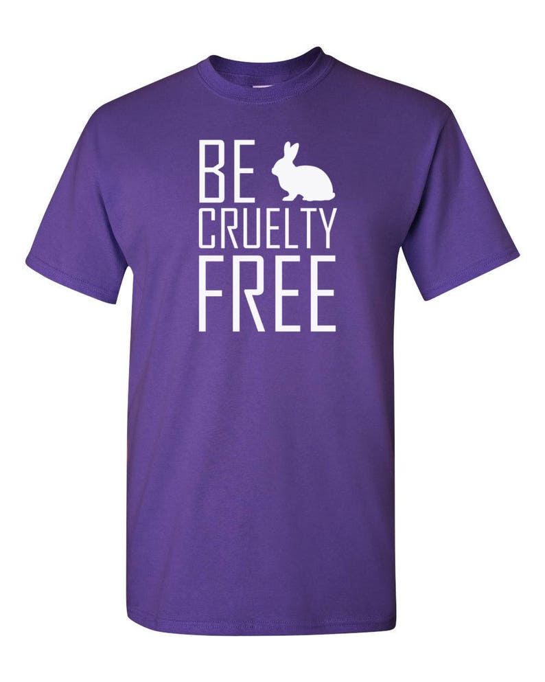 K&ouml;nnte beinhalten: Ein violettes Kurzarm-T-Shirt mit dem wei&szlig;en Schriftzug "BE", gefolgt von einer wei&szlig;en Kaninchensilhouette, wobei die W&ouml;rter "CRUELTY" und "FREE" darunter in Wei&szlig; gedruckt sind, alles mittig auf der Vorderseite.