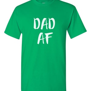 Peut inclure: T-shirt vert vif avec l'inscription blanche "DAD AF" dans un style manuscrit. Le t-shirt a des manches courtes et un col rond.