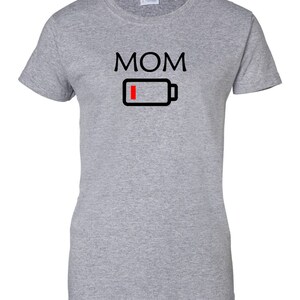 Pu&ograve; includere: T-shirt grigio melange con la scritta "MOM" in nero, sopra un'icona di batteria nera con una barra rossa che indica la batteria scarica. La maglietta &egrave; a girocollo.