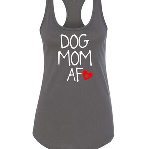 May include: A charcoal gray racerback tank top with the words "DOG MOM AF" in white, and a red heart graphic. The tank top has a scoop neck and a curved hemline. The shirt is made of a soft material.