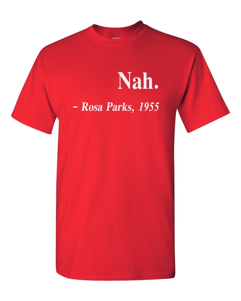 May include: A bright red t-shirt with the word "Nah." printed in white, followed by "- Rosa Parks, 1955." The shirt is a classic crew neck style, made of a soft material.