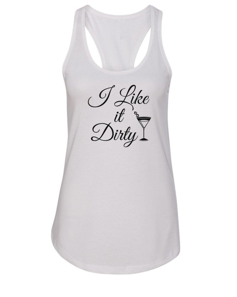 May include: White racerback tank top with the text "I Like it Dirty" in black script, accompanied by a martini glass illustration. The tank top has a scoop neck and a racerback design.