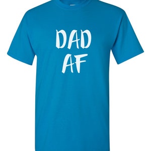 Peut inclure: Un t-shirt bleu turquoise avec le texte blanc "DAD AF" dans un style manuscrit. Le t-shirt a des manches courtes et un col rond.