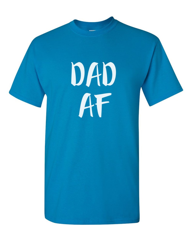 Peut inclure: Un t-shirt bleu turquoise avec le texte blanc "DAD AF" dans un style manuscrit. Le t-shirt a des manches courtes et un col rond.