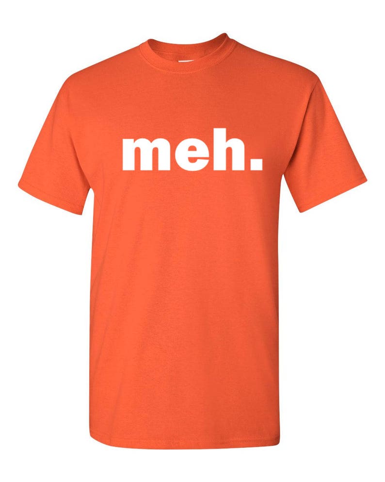 May include: Orange t-shirt with the word "meh." printed in white. The shirt has short sleeves and a crew neck. The text is centered on the front of the shirt.