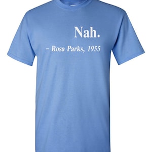 May include: Light blue t-shirt with the text "Nah." and "- Rosa Parks, 1955" printed in white. The shirt has short sleeves and a crew neck.