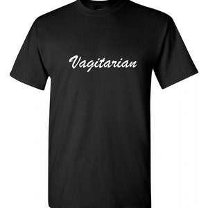 May include: Black t-shirt with the word "Vagitarian" printed in white script across the chest. The shirt has short sleeves and a crew neck. The fabric appears to be a soft cotton blend.