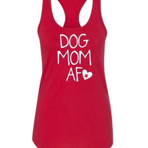 May include: A red racerback tank top with the words "DOG MOM AF" in white, along with a white heart and paw print graphic. The tank top has a scoop neck and a sleeveless design.