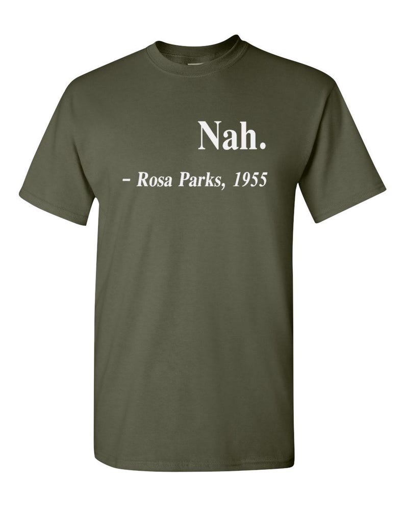 May include: Olive green t-shirt with the text "Nah." above "- Rosa Parks, 1955" in white. The shirt is a crew neck style and appears to be made of a soft material.