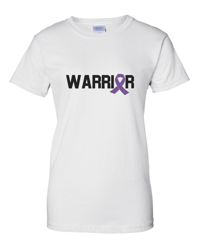 Puede incluir: Camiseta blanca con la palabra "WARRIOR" en letras negras y una cinta morada de concienciaci&oacute;n que reemplaza la letra "R". La camiseta est&aacute; hecha de un material suave y c&oacute;modo.