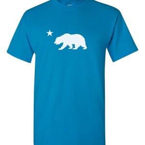 May include: A turquoise blue t-shirt with a white silhouette of a bear and a star.