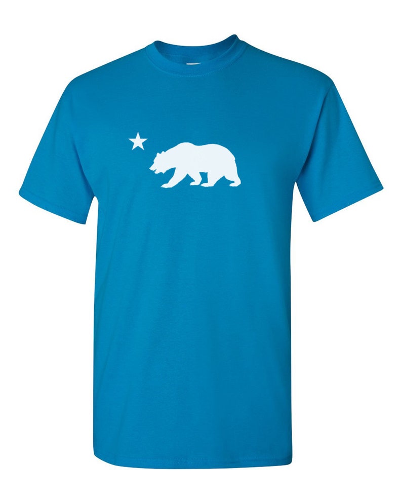 May include: A turquoise blue t-shirt with a white silhouette of a bear and a star.