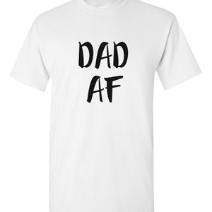 Peut inclure: T-shirt blanc avec l'inscription noire "DAD AF" dans un style manuscrit audacieux. Le t-shirt a un col rond classique et des manches courtes. Le texte est centr&eacute; sur le devant du v&ecirc;tement.