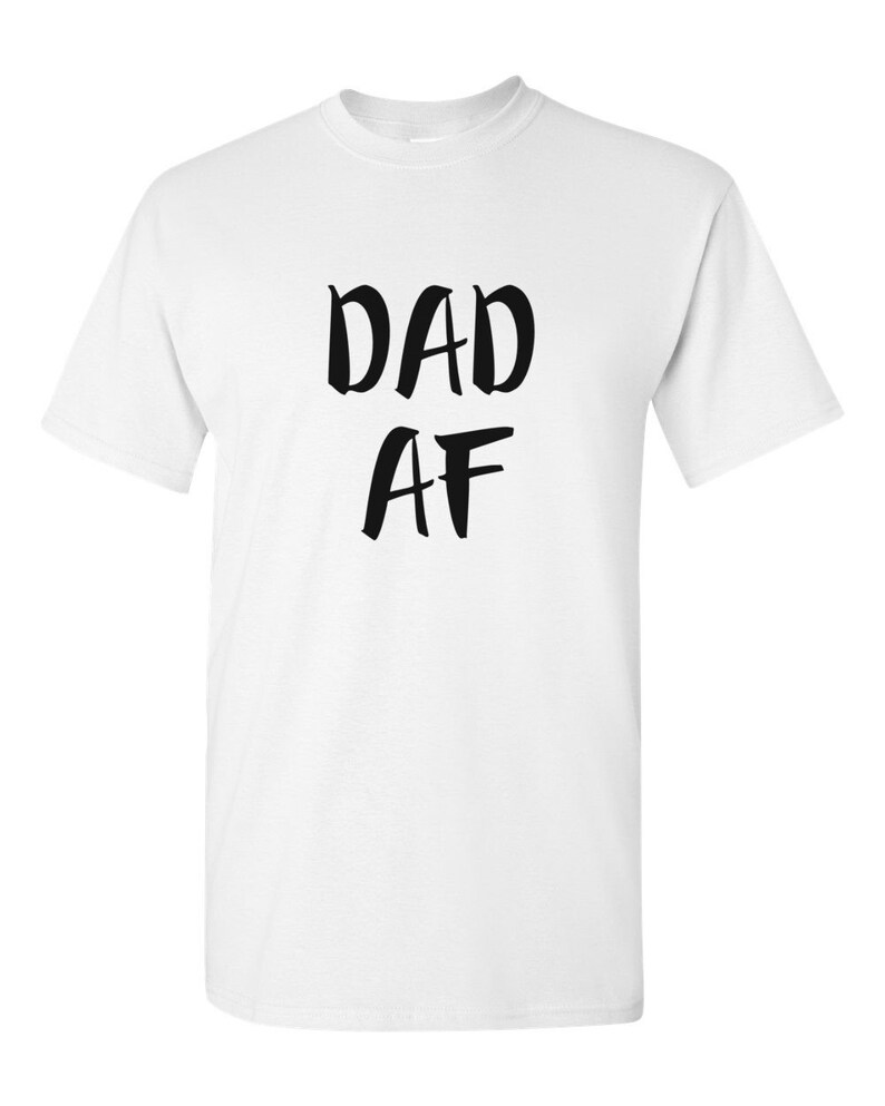Peut inclure: T-shirt blanc avec l'inscription noire "DAD AF" dans un style manuscrit audacieux. Le t-shirt a un col rond classique et des manches courtes. Le texte est centr&eacute; sur le devant du v&ecirc;tement.