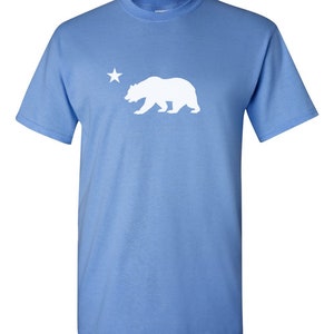 May include: A light blue t-shirt with a white silhouette of a bear and a star.