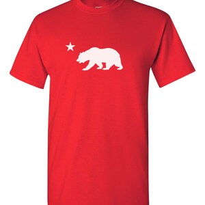May include: Red t-shirt with a white silhouette of a bear and a star.