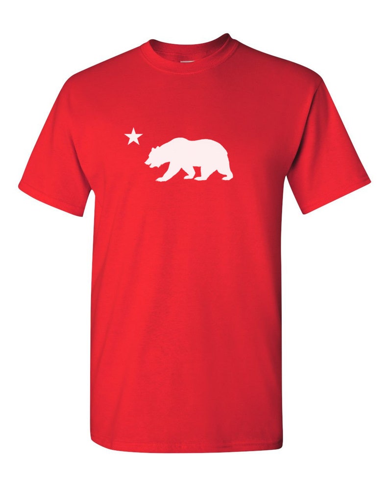 May include: Red t-shirt with a white silhouette of a bear and a star.
