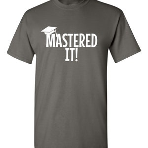 K&ouml;nnte beinhalten: Ein dunkelgraues T-Shirt mit dem wei&szlig;en Schriftzug &bdquo;MASTERED IT!&ldquo; und einer Abschlusskappe. Dieses T-Shirt mit Rundhalsausschnitt eignet sich f&uuml;r den l&auml;ssigen Gebrauch und zum Feiern akademischer Erfolge.