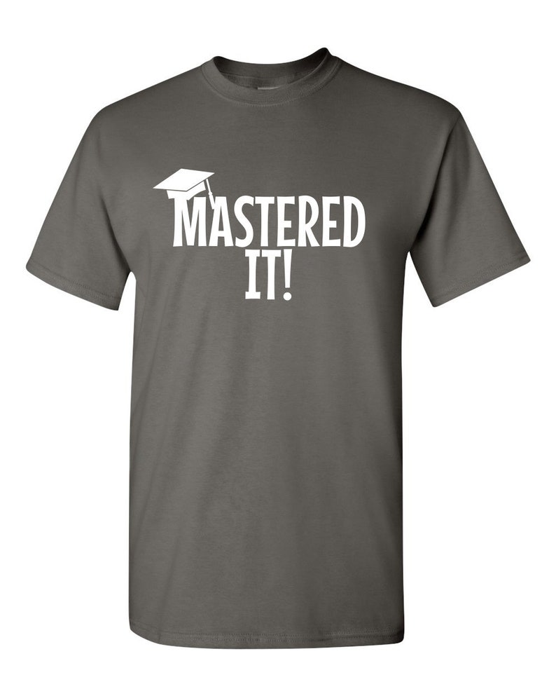 K&ouml;nnte beinhalten: Ein dunkelgraues T-Shirt mit dem wei&szlig;en Schriftzug &bdquo;MASTERED IT!&ldquo; und einer Abschlusskappe. Dieses T-Shirt mit Rundhalsausschnitt eignet sich f&uuml;r den l&auml;ssigen Gebrauch und zum Feiern akademischer Erfolge.