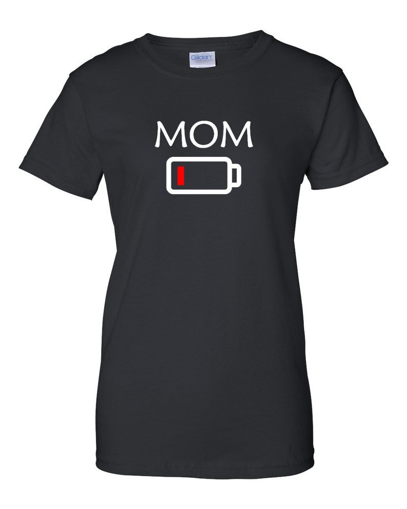 Pu&ograve; includere: T-shirt nera con la scritta "MOM" in lettere maiuscole bianche sopra un'icona di batteria bianca con una barra rossa che indica batteria scarica. Girocollo.