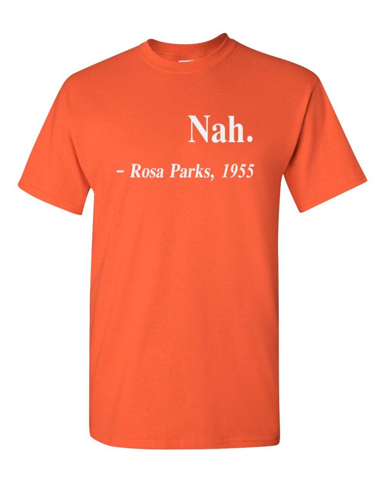 May include: Bright orange t-shirt with the text "Nah." and "- Rosa Parks, 1955" printed in white. The shirt is a short-sleeved crew neck style.