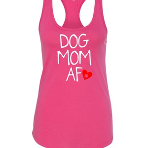 May include: A bright pink racerback tank top with the words "DOG MOM AF" in white block letters. A red heart with a paw print is below the text. The tank top has a scoop neck and a racerback design.