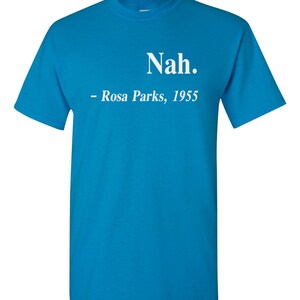 May include: A turquoise t-shirt with the word "Nah." printed in white, followed by "- Rosa Parks, 1955." The shirt is a short-sleeved crew neck style. The text is centered on the front of the shirt.
