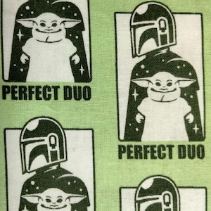 Pode incluir: Tecido verde claro com um padrão repetido de ilustrações a preto e branco. Cada ilustração mostra uma personagem com um capacete e uma criatura semelhante a um bebé, com o texto "PERFECT DUO" por baixo. O tecido tem um aspeto texturizado.