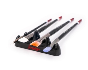 May include: Four paint brushes with black handles and different colored bristles are arranged in a black plastic holder. The holder has the word "Angelus" printed on it in red.