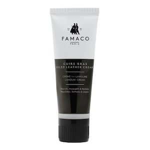 Puede incluir: Un tubo blanco de crema para cuero engrasado Famaco Paris Cuirs Gras con texto negro y una tapa negra. El texto dice "Cuirs Gras Oiled Leather Cream", "Creme ala Lanoline Lanolin Cream", "Nourrit, Assouplit & Nettoie", y "Nourishes, Softens & Cleans".