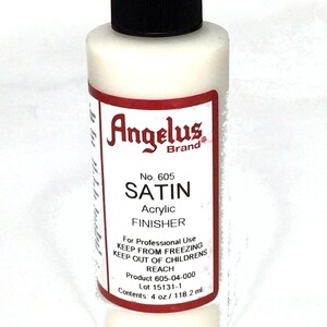 May include: A white bottle of Angelus Brand Satin Acrylic Finisher. The bottle is labeled with the product name, number, and instructions for use. It contains 4 ounces or 118.2 milliliters of product.