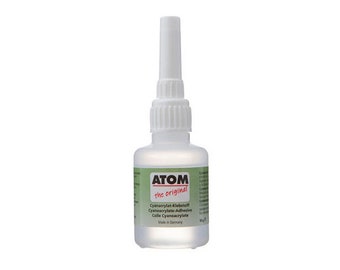 Könnte beinhalten: Eine durchsichtige Plastikflasche mit Atom-Marken-Cyanacrylat-Klebstoff, auch bekannt als Sekundenkleber. Die Flasche ist mit "the original" beschriftet und hat einen weißen Verschluss mit einer langen, dünnen Applikatorspitze. Das Etikett trägt außerdem die Aufschrift "Cyanacrylate Adhesive" und "Made in Germany".