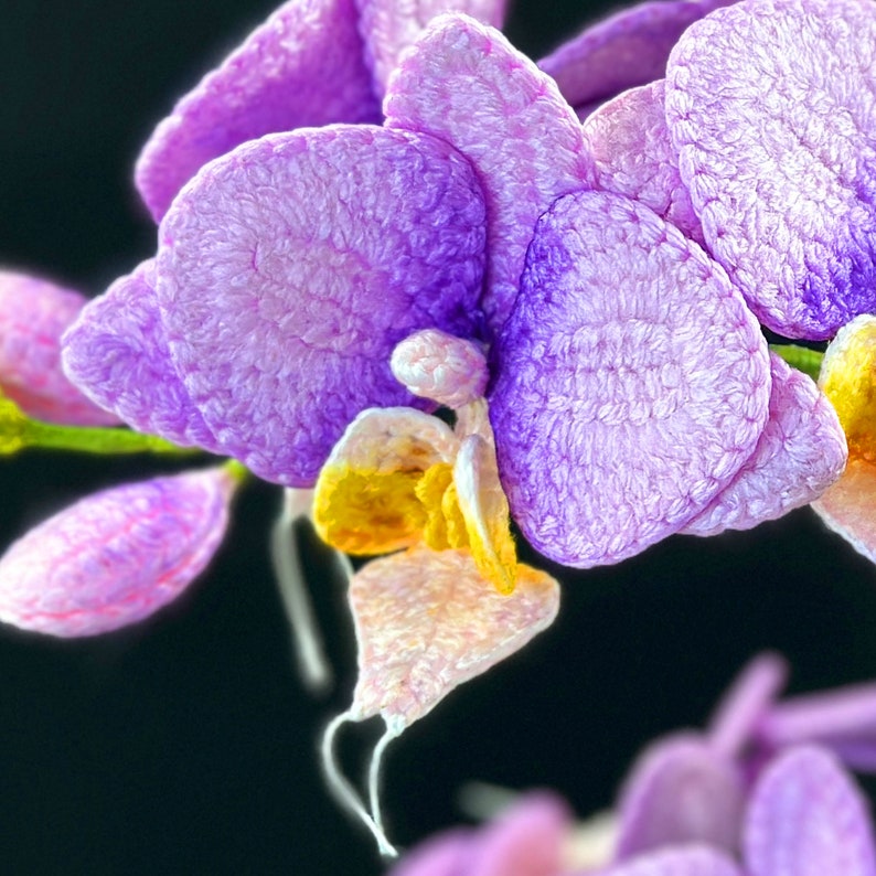 May include: A close-up of a purple and yellow orchid flower. The flower is made of fabric and has a soft, fuzzy texture.