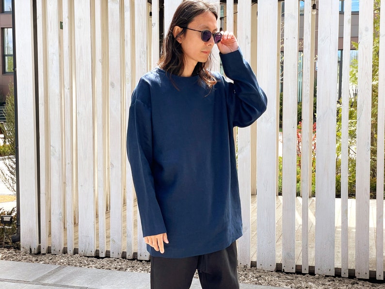 May include: A navy blue long-sleeved shirt with a relaxed fit. The shirt has a crew neck and is made of a soft, comfortable fabric.